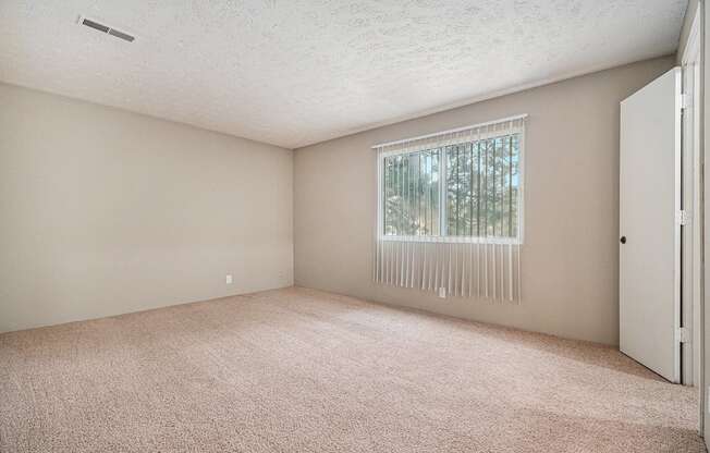Omaha, NE Evergreen Terrace Apartments. A bedroom with a large window and beige carpet