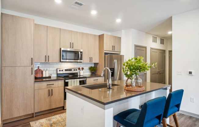 a kitchen with wooden cabinets and a island with blue chairs