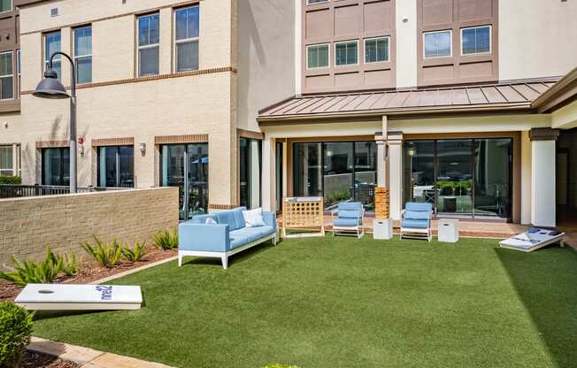 a yard with a couch and chairs in front of a building