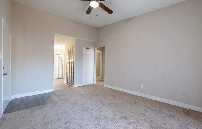 a living room with white walls and a ceiling fan