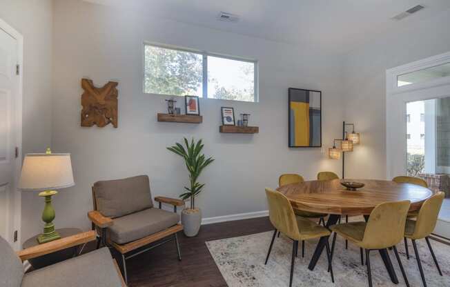 a dining area with a round wooden table and yellow chairs at Seasons at Umstead apartments in Raleigh