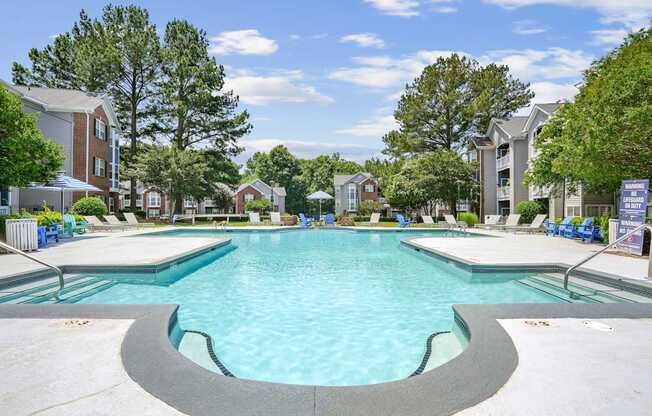A large swimming pool in a residential area with trees and houses in the background.