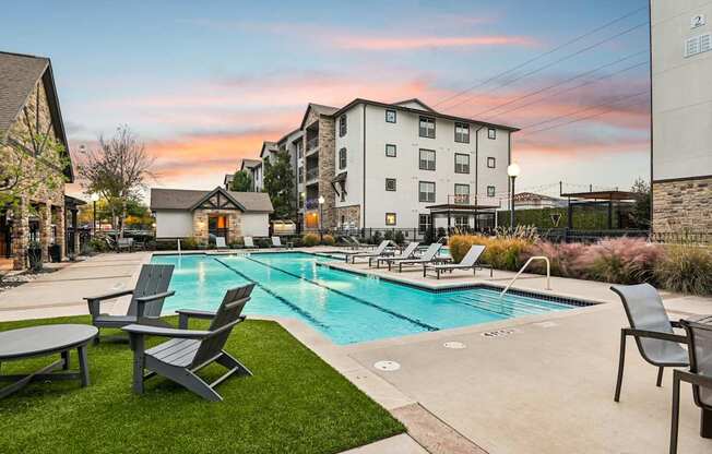 A pool surrounded by lawn chairs and a building in the background.