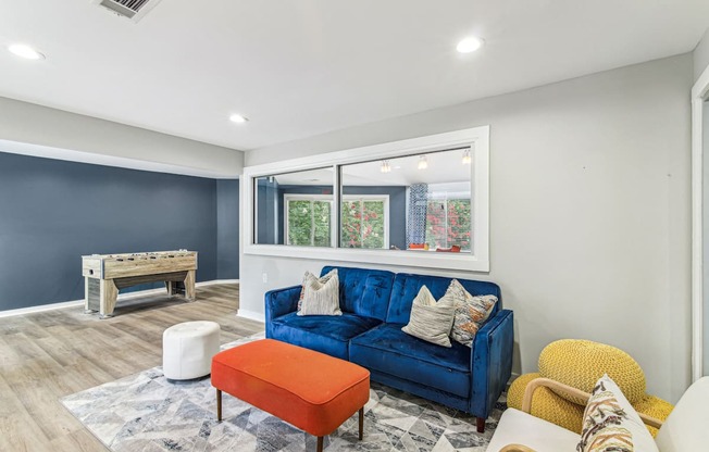 A blue couch with a white pillow is in the middle of a room with a window.