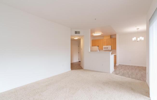 A white room with a carpet and a kitchen area in the background at Cornerstone at Gale Ranch Apartments, San Ramon, CA, 94582