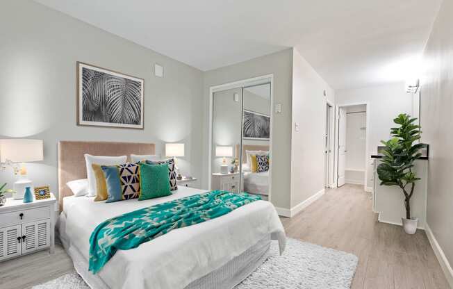 Bedroom with mirrored closet doors and a vanity area with wood-inspired floors throughout