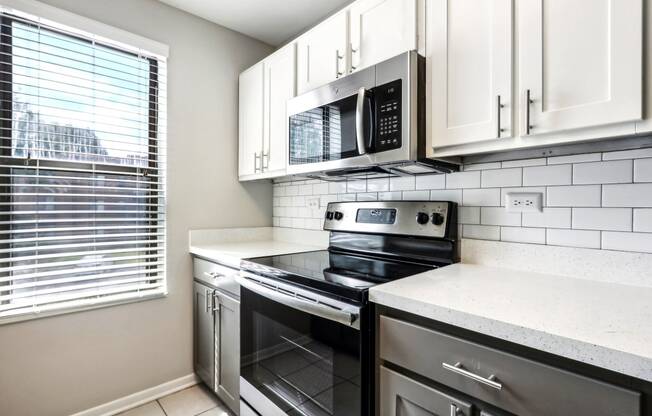 an empty kitchen with black appliances and white cabinets