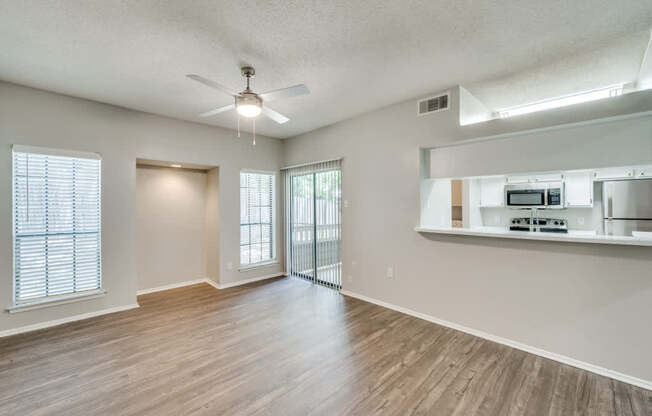 an empty living room with a ceiling fan and a kitchen at Foxborough Apartments, Irving, TX, Texas, 75061
