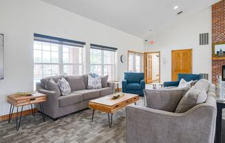 Lounging area in clubhouse with couches and chairs and a brick fireplace in the back