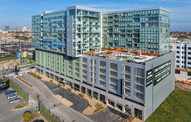 A modern glass building with a parking lot in front.