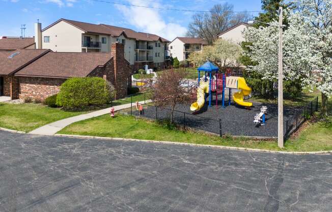a playground in a neighborhood with houses and children playing on it