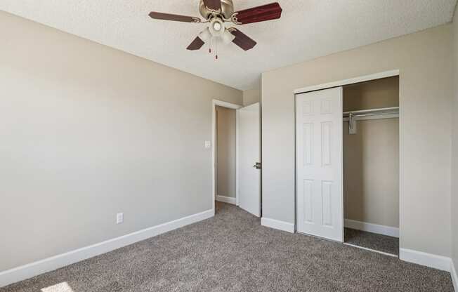 A room with a ceiling fan and carpeted floor.