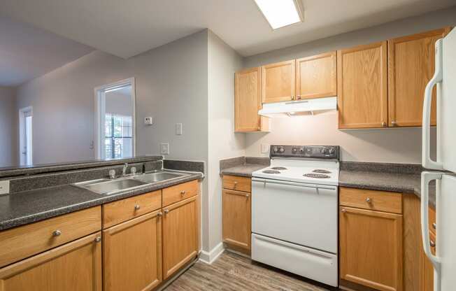 an empty kitchen with white appliances and wooden cabinets at Crogman School Lofts, Georgia