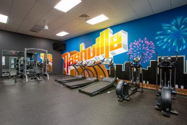 A gym with a variety of equipment including treadmills, stationary bikes, and weight machines.