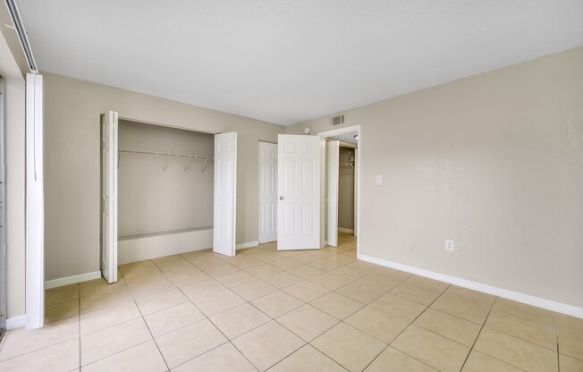 an empty living room with a tiled floor and a closet