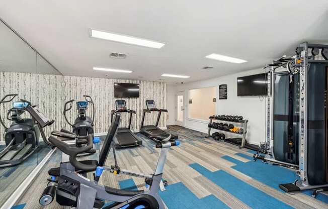 A gym with a variety of equipment including treadmills, stationary bikes, and weight machines.