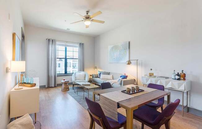 a living room with white walls and a ceiling fan