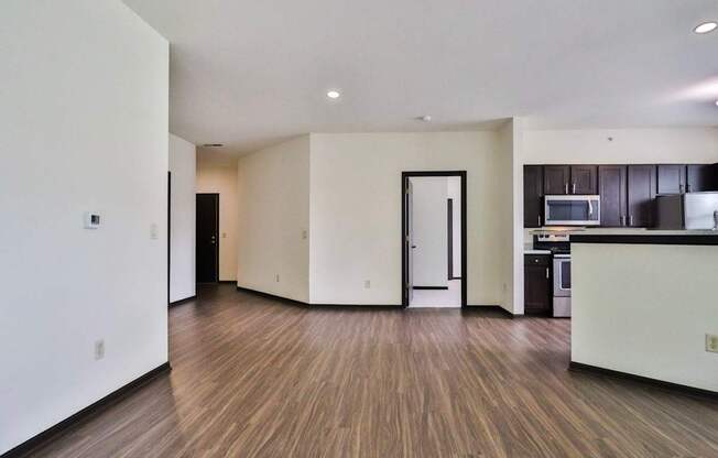 A modern kitchen with dark wood floors and white walls.