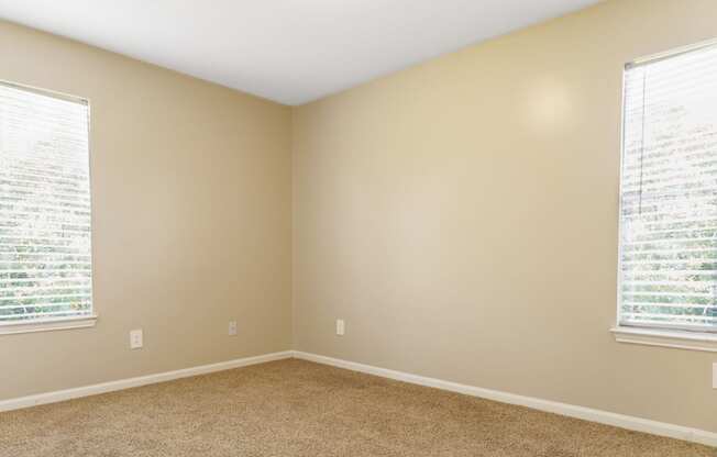 a bedroom with two windows and a carpeted floor