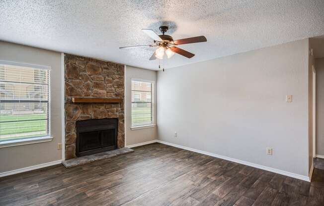 Living Room with Fireplace and Ceiling Fan at Bookstone and Terrace Apartments in Irving, Texas