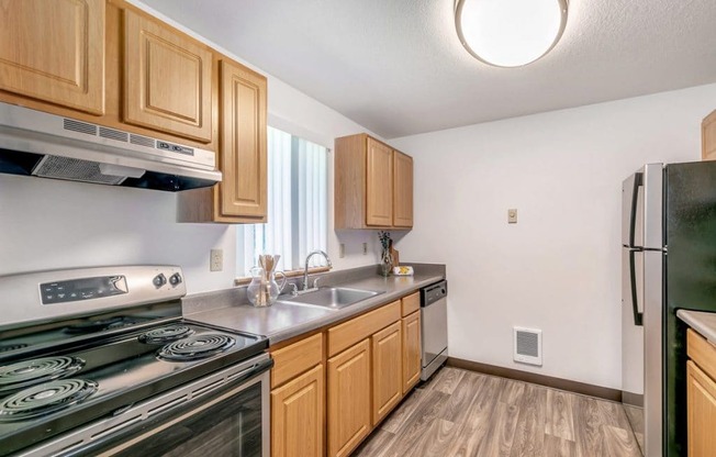 A kitchen with wooden cabinets and a black stove top oven.at Alder Creek Apartments, Vancouver, WA 98682