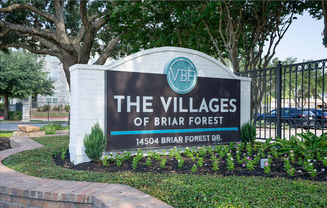 A sign for The Villages of Briar Forest stands in front of a tree.