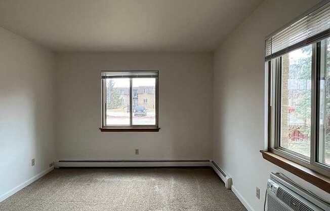 A room with a window and a carpeted floor.