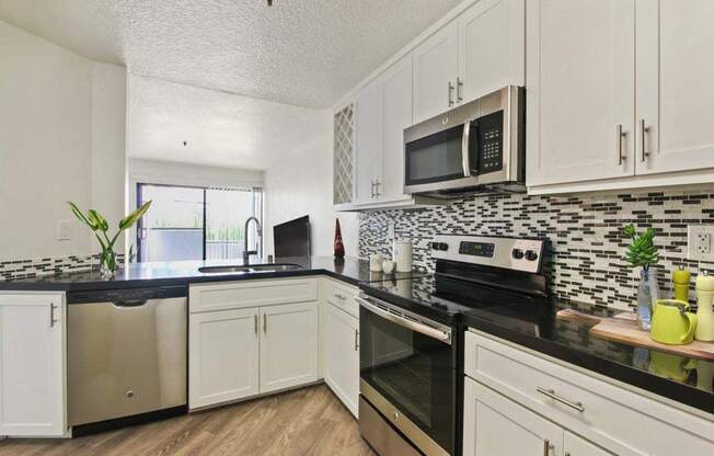 a kitchen with white cabinets and black counter tops  at Masselin Park West, Los Angeles, CA