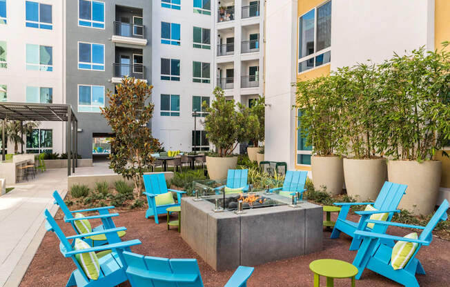 A patio with blue chairs and a fire pit.