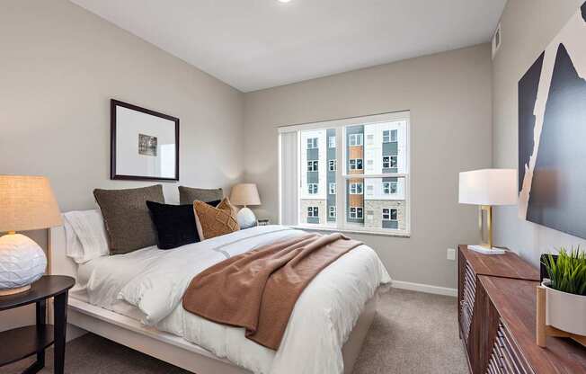 A bedroom with a large bed and a window showing a cityscape.