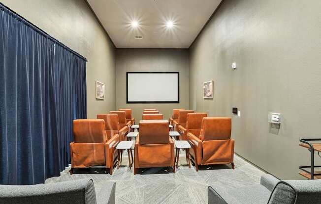 Movie room with theatre style chairs and a projector screen at GreenVue apartments in Richardson, TX