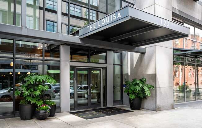 The Louisa building has a glass entrance with a black mat in front.