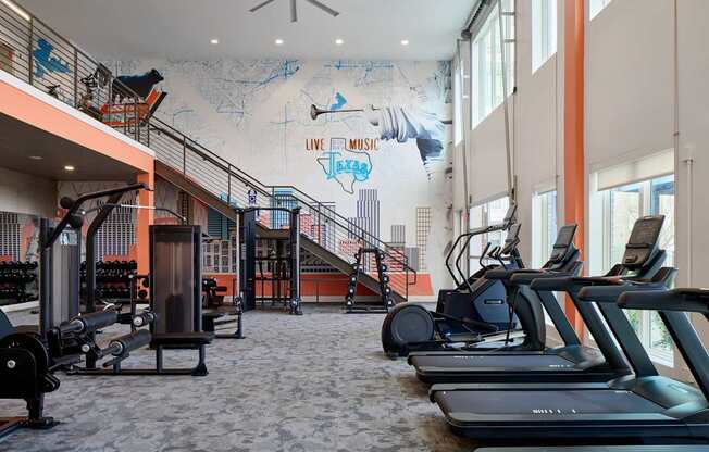 A gym with treadmills, weights and a staircase.