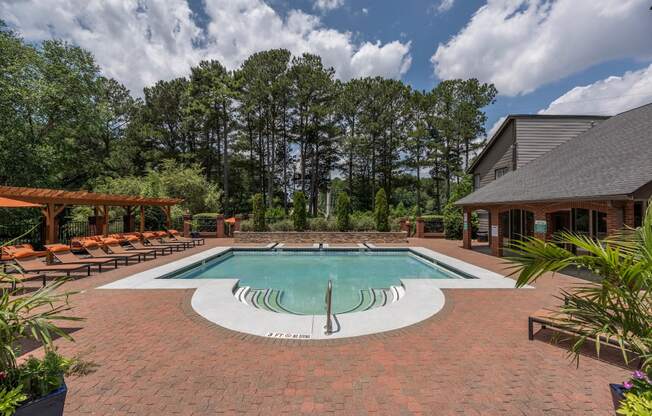 a pool with chairs and a house with trees in the background