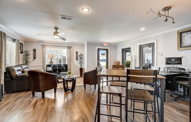 a living room with a couch a table and chairs and a ceiling fan