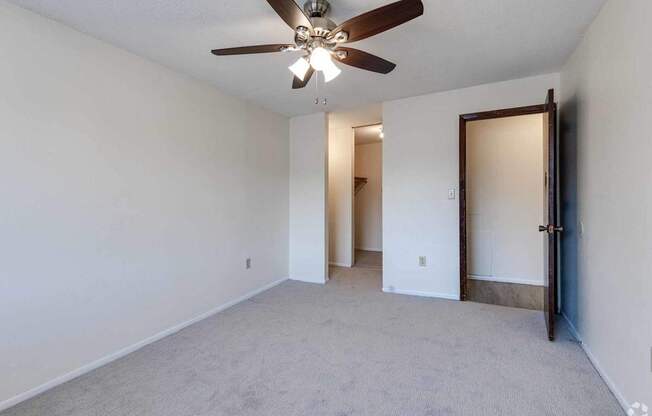 A room with a ceiling fan and carpeted floor.