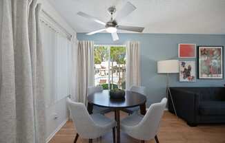 a living room with a table and chairs and a ceiling fan