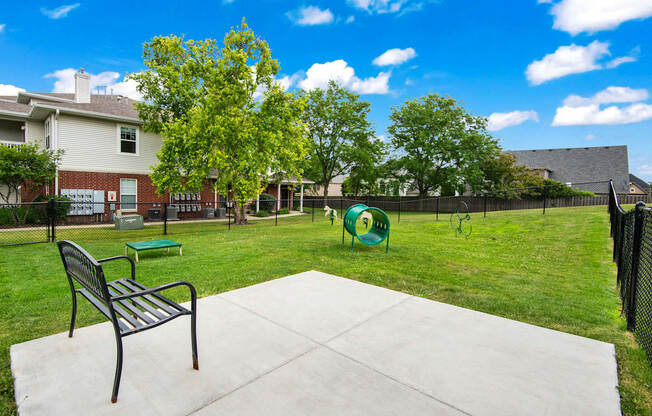 A park with a bench and a green ball in the middle of the grass.