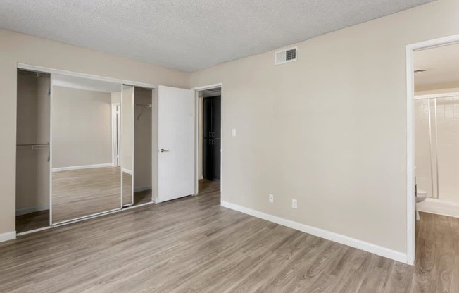 Pet-Friendly Apartments in Tempe – Sentry Tempe – an empty living room with wood flooring and a mirrored closet