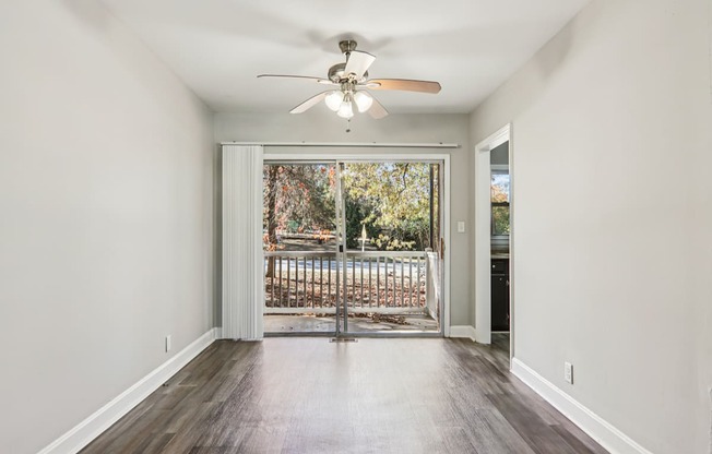 A room with a ceiling fan and sliding glass doors.