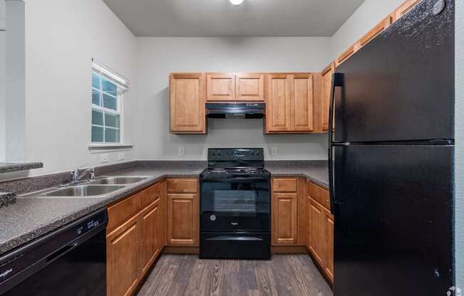 A black refrigerator sits in a kitchen with wooden cabinets.