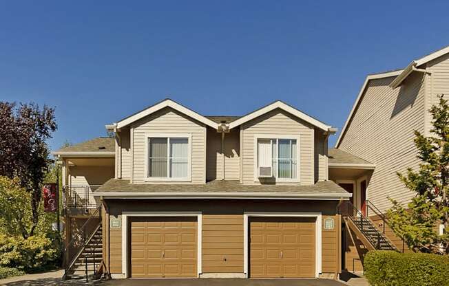 a tan house with two garage doors