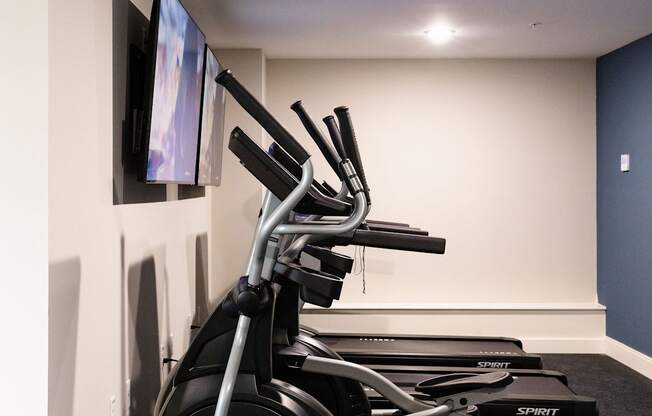 A row of stationary bikes are lined up in a room.