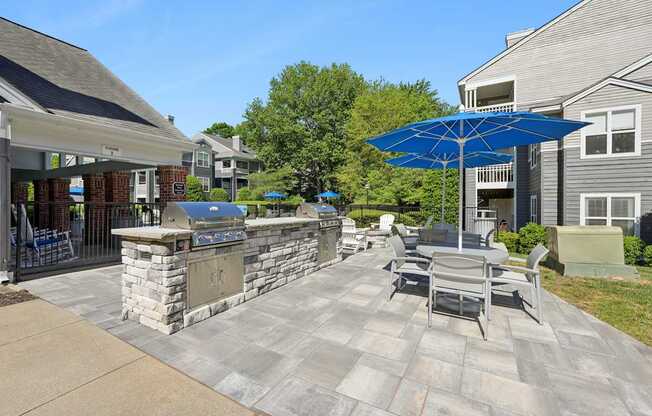 A patio with a stone wall and a blue umbrella.