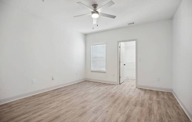 A room with a ceiling fan and wooden flooring.