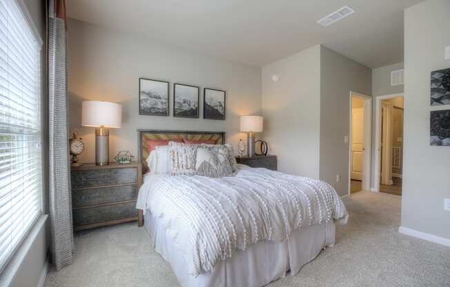 Furnished model bedroom with a window and carpet flooring at Lullwater at Blair Stone apartments for rent