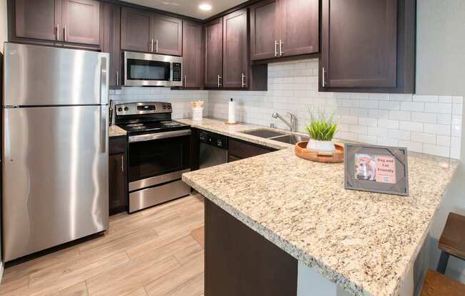 A kitchen with a granite counter top and stainless steel appliances.