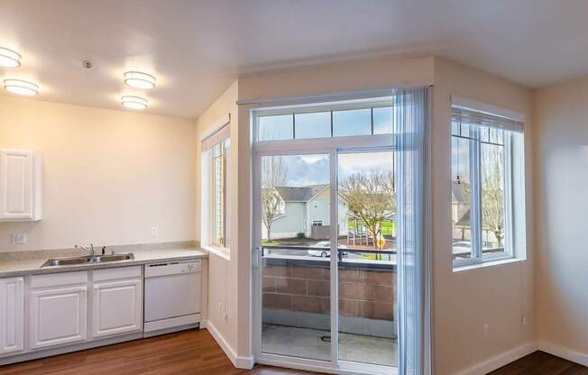 A kitchen with white cabinets and a view of the outside through the glass doors.