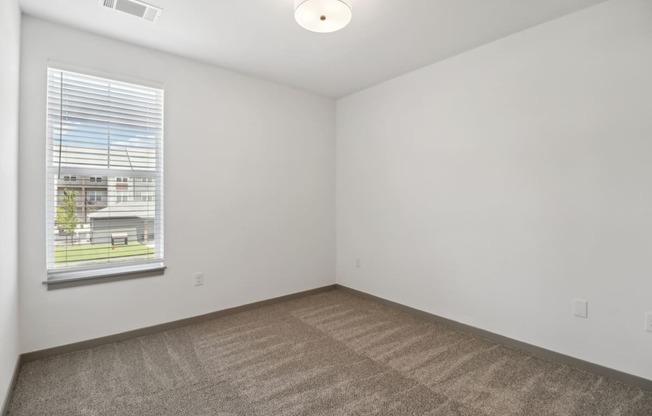 the living room of an apartment with carpet and a window at The Depot in The Depot Raymore, MO 64083