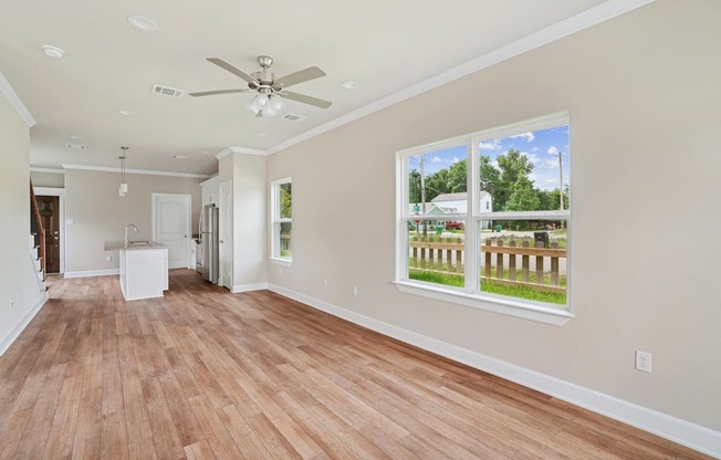 A room with a ceiling fan and a large window.